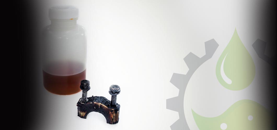 oil in a plastic bottle next to a grime and rust covered gear